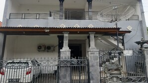 Un immeuble de deux étages doté d’un balcon, d’une antenne parabolique et d’une entrée fermée par un portail.