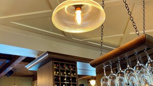 Un espace bar avec un présentoir à bouteilles de vin, des bouteilles et des verres.