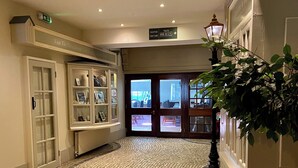 Un hall d’entrée avec un sol pavé de pierres, des vitrines et un comptoir d’accueil.