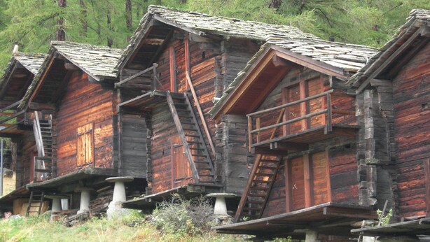 Una hilera de cabañas de madera rústicas con techos a dos aguas, construidas en la ladera de una colina.