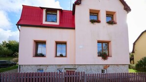 A two-story building with a red roof and pink walls, featuring multiple windows and flower boxes. - Formanka by Interhome (Liberec)