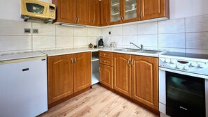 A kitchen with wooden cabinets, a microwave, a stove, and a dishwasher. - Formanka by Interhome (Liberec)