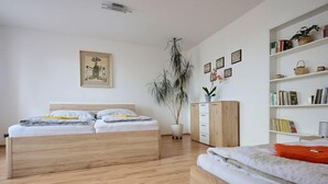 A bedroom with two beds, a wooden wardrobe, a bookshelf, and a potted plant. - Formanka by Interhome (Liberec)