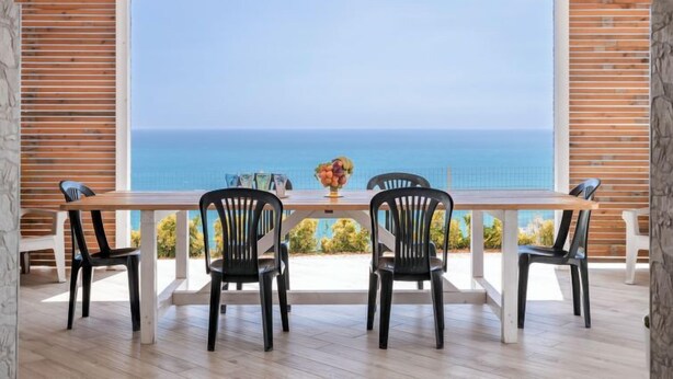 Un comedor con una mesa y cuatro sillas, con vistas a un paisaje marino.
