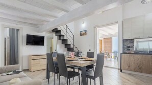 Un espacio de estar moderno con comedor, cocina y escalera.