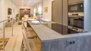 Une cuisine moderne dotée d’un îlot central, de tabourets de bar, d’un four encastré et d’un four à micro-ondes.