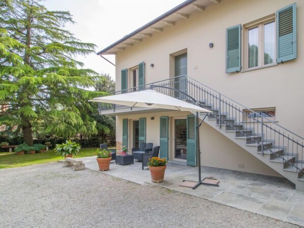 A two-story house with a covered patio, outdoor seating, and a staircase.