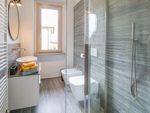 A modern bathroom with a glass shower enclosure, a white sink, and a toilet.
