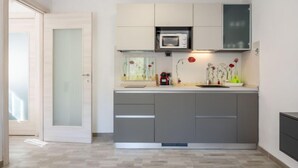 Een moderne keuken met grijze kastjes, een magnetron en een spoelbak.