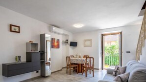 Een moderne woonkamer met een bank, een eettafel met stoelen, een ingebouwde televisie en een balkon met uitzicht.