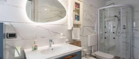 Un baño moderno con tocador de mármol, ducha con cerramiento de vidrio y un bidé.