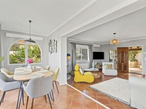 Uma sala ampla com mesa de jantar, cadeiras, sofá e televisão.