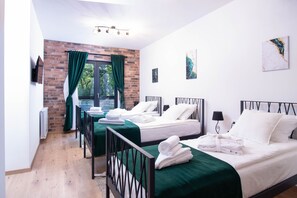 A hotel room with two beds, green curtains, a brick wall, and artwork on the walls. -  VILLA PORTUM - Serenity, Nature, Heated Pool, FAMILY ONLY (Labin)
