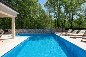 A swimming pool with lounge chairs and a stone wall. -  VILLA PORTUM - Serenity, Nature, Heated Pool, FAMILY ONLY (Labin)