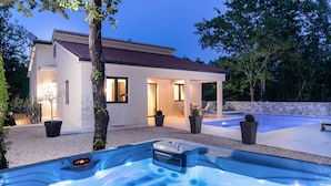 A modern house with a hot tub, outdoor seating, and a swimming pool.