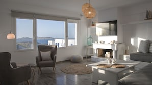 Ein modernes Wohnzimmer mit großen Fenstern, einem Kamin und Meerblick.