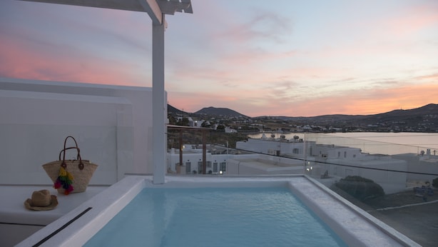Ein Dachpool mit Blick auf eine Stadt und Berge bei Sonnenuntergang.