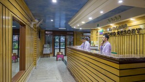 Un comptoir d'accueil à l'hôtel Avocado Orchid Resort, avec un intérieur en bois et une vue dégagée sur l'espace de réception.