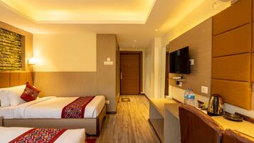 A hotel room with two beds, a wooden headboard, a flat-screen TV, a coffee maker, and a small kitchenette.