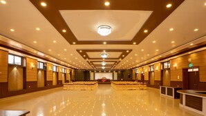 Un hall d’hôtel spacieux, dot é d’un sol en marbre poli, de rangées de sièges et d’une scène centrale.