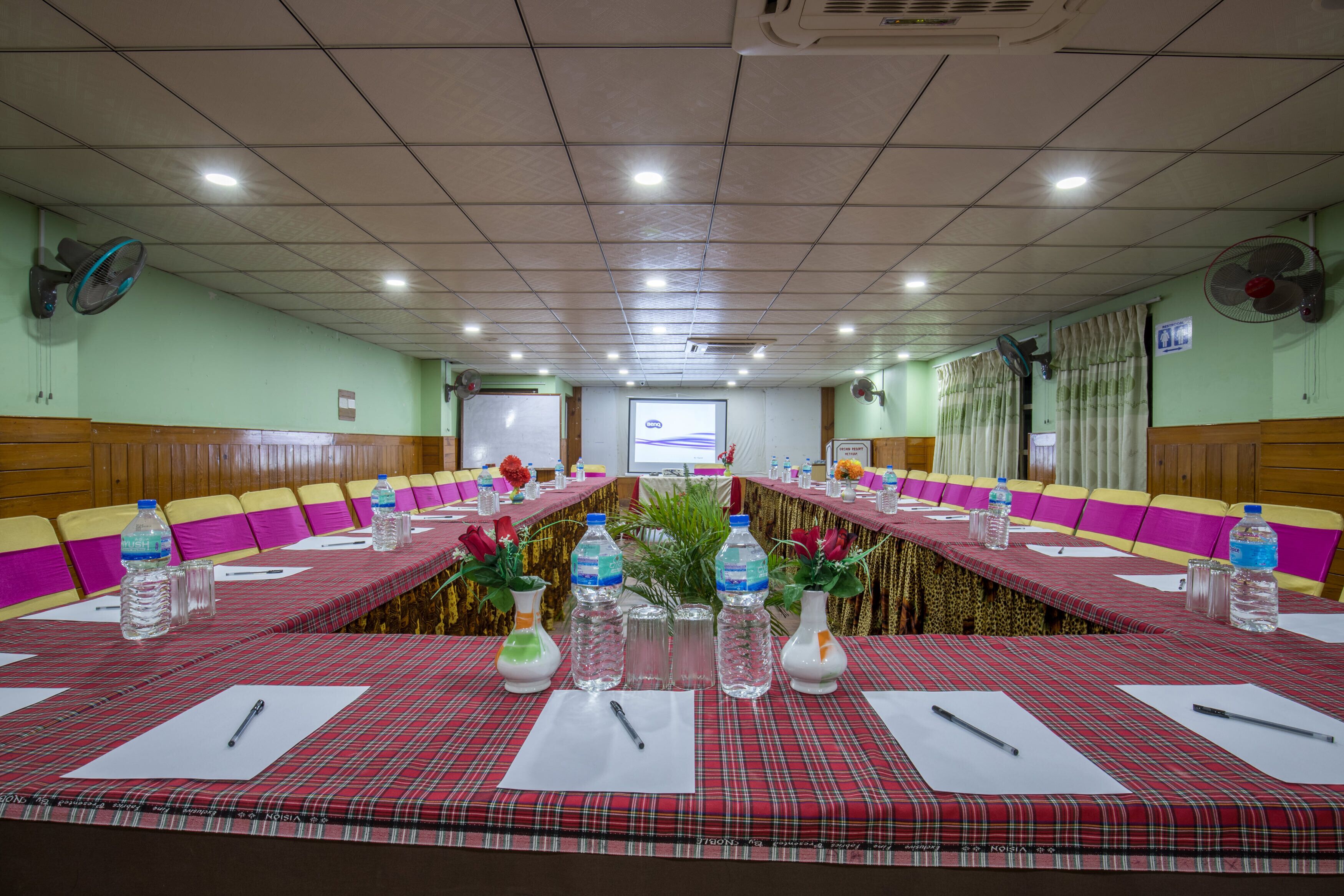 Un salón de conferencias con una larga mesa, sillas y botellas de agua.