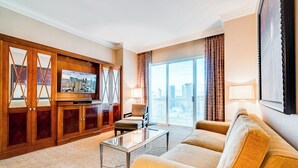 Hotellihuone, jossa on suuri ikkuna, sohva, televisio ja puukalusteet.