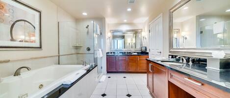 A modern bathroom with a large bathtub, a separate shower area, and a vanity with a mirror.