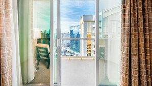 Ein Balkon mit Blick auf die Stadt, ein Stuhl und ein Tisch mit Lampe.