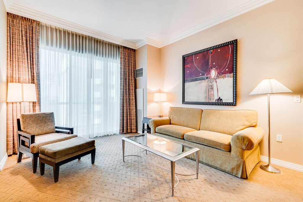 Une chambre d’hôtel avec un canapé, un fauteuil et une table basse en verre.