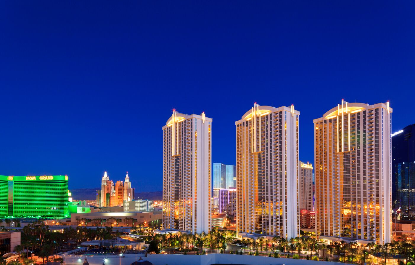 A high-rise hotel with multiple floors, a prominent casino in the background, and a well-lit urban skyline.