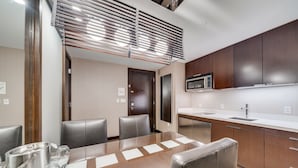 A modern kitchen with dark wooden cabinets, a stainless steel microwave, and a white countertop. - Vdara Studio by Jet Luxury (Las Vegas)