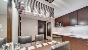 A modern kitchen with dark wooden cabinets, a stainless steel microwave, and a white countertop. - Vdara Adjoining Parlor Suite by Jet Luxury (Las Vegas)