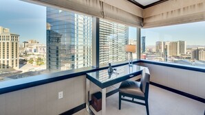 Ein modernes Hotelzimmer mit großem Fenster und Blick auf die Stadt, einem Glastisch und einem Stuhl.