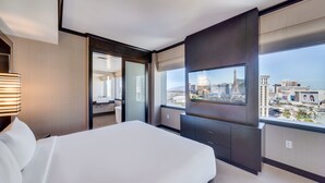 Ein modernes Hotelzimmer mit einem großen Bett, einem Fernseher und Blick auf die Stadt.