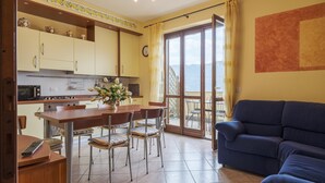 Eine Küche mit Esstisch und Stühlen, einer Couch und Blick durch eine Glastür.