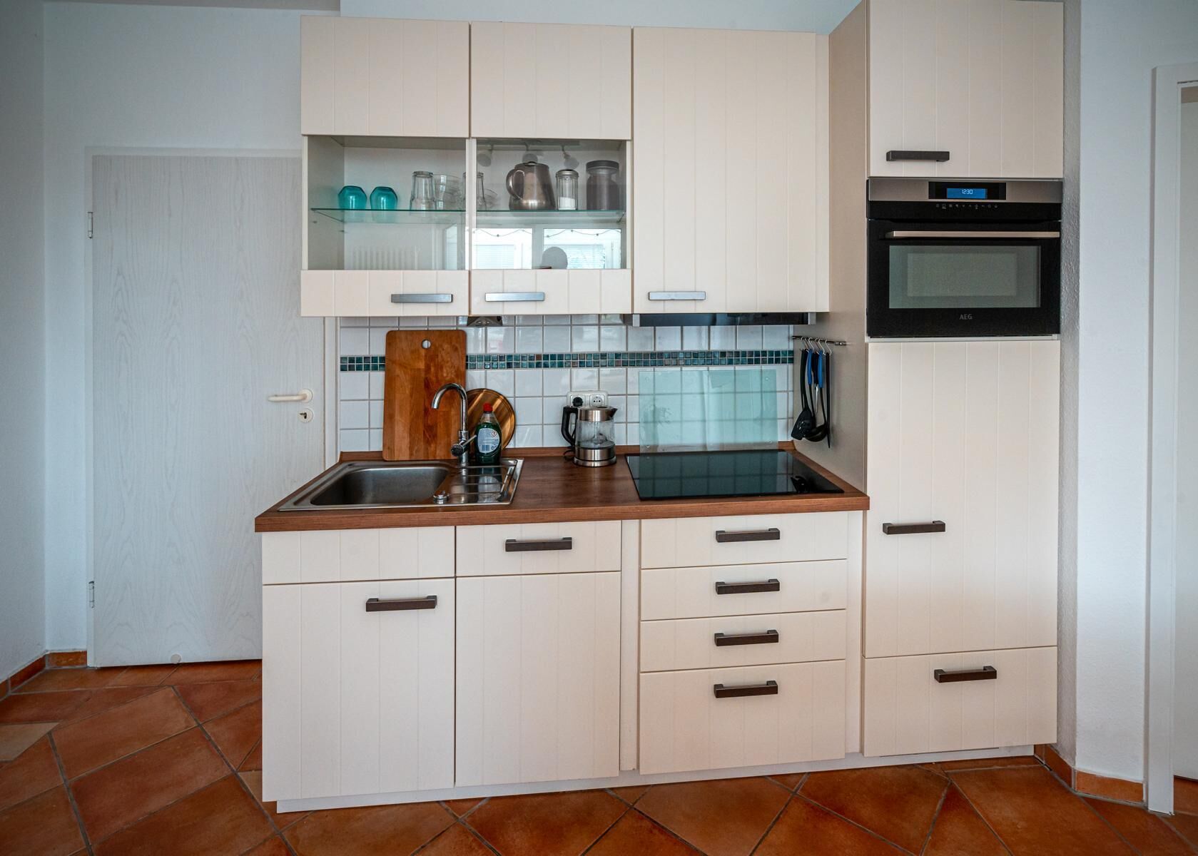 A compact kitchen with white cabinets, a black oven, and a stainless steel sink.