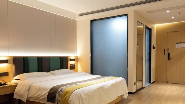 Een hotelkamer met een bed, nachtlampjes, een kledingkast en een deur.