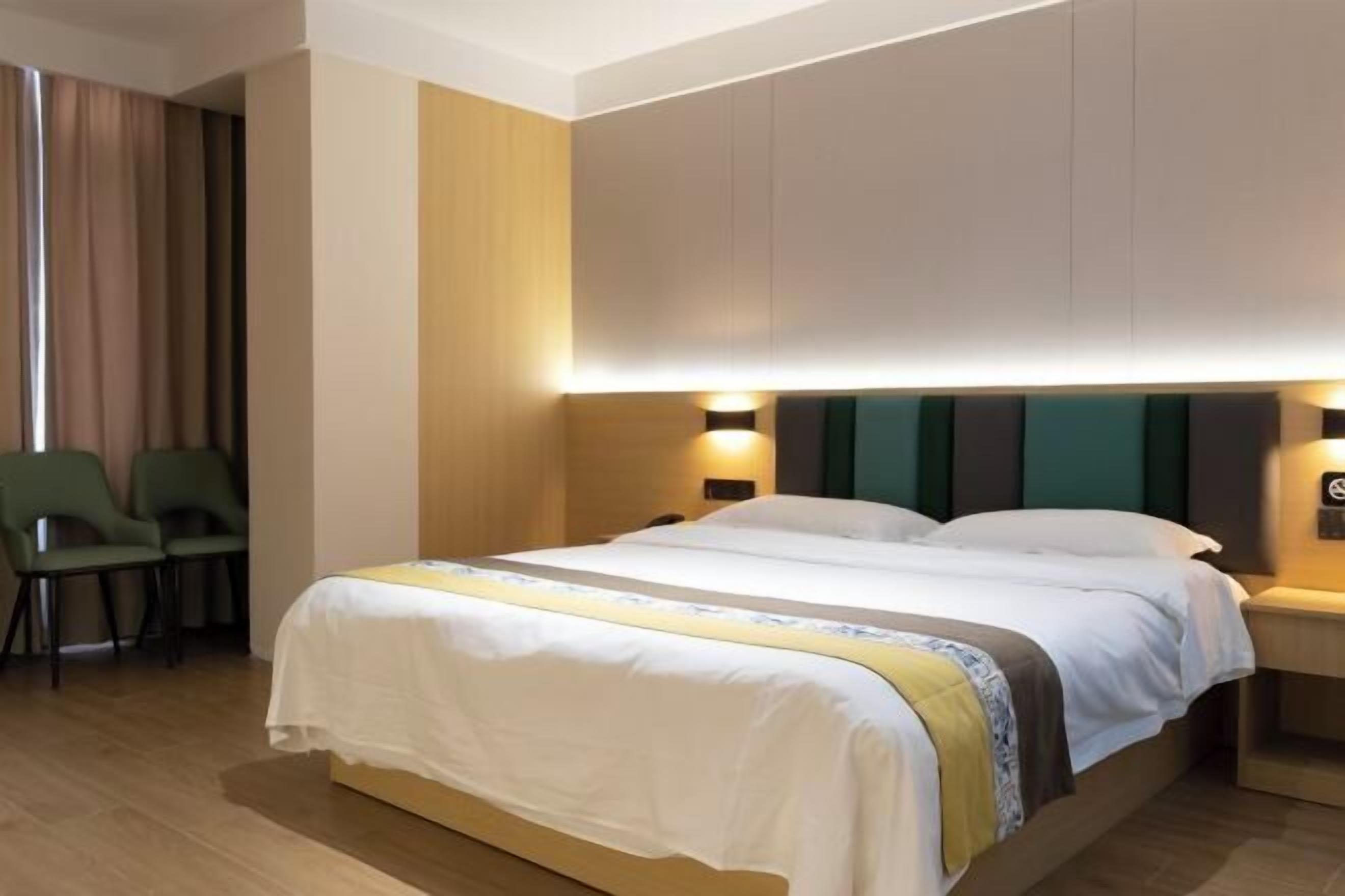 Una habitación de hotel con una cama, dos mesitas de noche, una silla y una cortina.