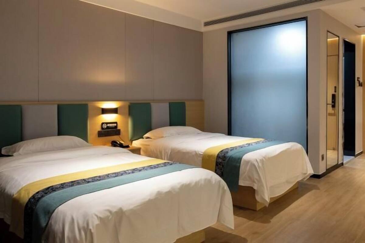 Habitación de hotel con dos camas, una mesita de noche, teléfono en la pared y una puerta corredera.
