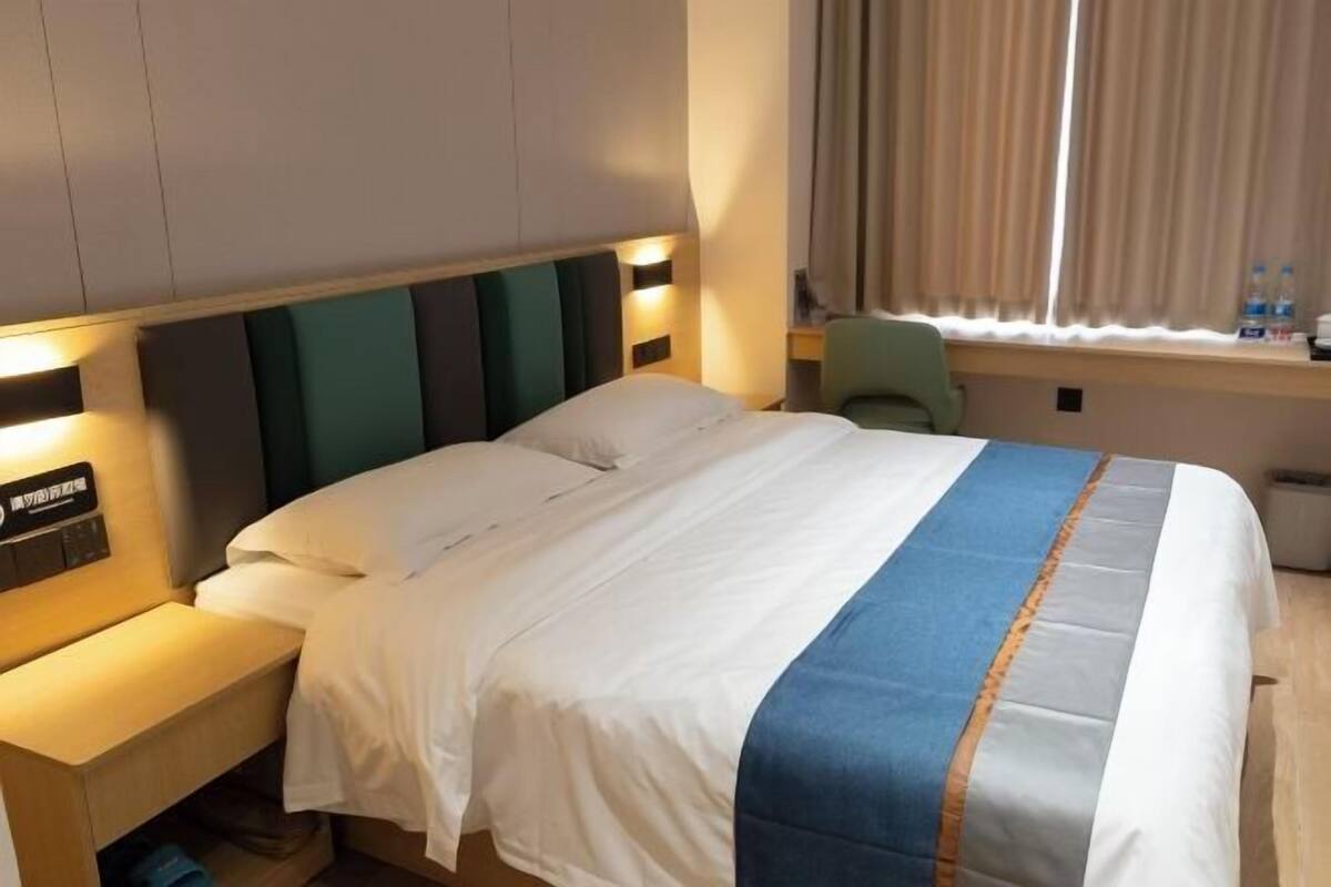 Una habitación de hotel con una cama, una mesita de noche y una ventana con cortinas.