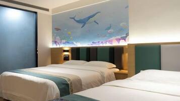 A hotel room with two beds, a mural of marine life on the wall, and a nightstand with a lamp.