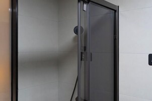 Cabina de ducha con paredes de vidrio, panel de control y ducha visible.