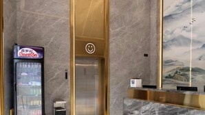 Een hotel receptie met een marmeren vloer, een automaat, een receptiebalie en een schilderij van bergen.