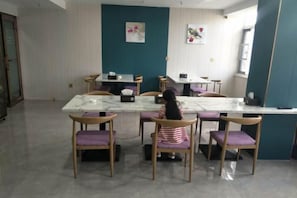 Un comedor con una mesa de mármol rodeada de sillas de madera, una pared de acento color aguamarina y un ventanal que proporciona luz natural.