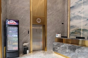 Un área de recepción con máquina expendedora, ascensor y una pared con un mural.