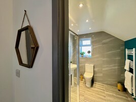 Un baño moderno con inodoro, lavabo y zona de ducha.
