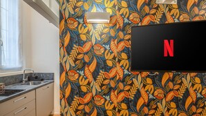 A kitchen with a patterned wall, a sink, and a flat-screen TV displaying the Netflix logo. - [Mini Loft Milano-Buenos Aires] WiFi-Netflix-Metro (Milano)