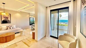 Una sala de estar moderna con un sofá, una mesa de centro y vista al océano a través de amplios ventanales correderos.