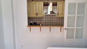 A compact bedroom with a single bed, a small bedside table, and a kitchenette with wooden cabinets and a tiled backsplash. - FIRST LINE OF BEACH AND DOWNTOWN. PEARL 5 (fuengirola)