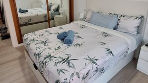 Ein Schlafzimmer mit Bett, Nachttisch, Spiegel und Kleiderschrank.